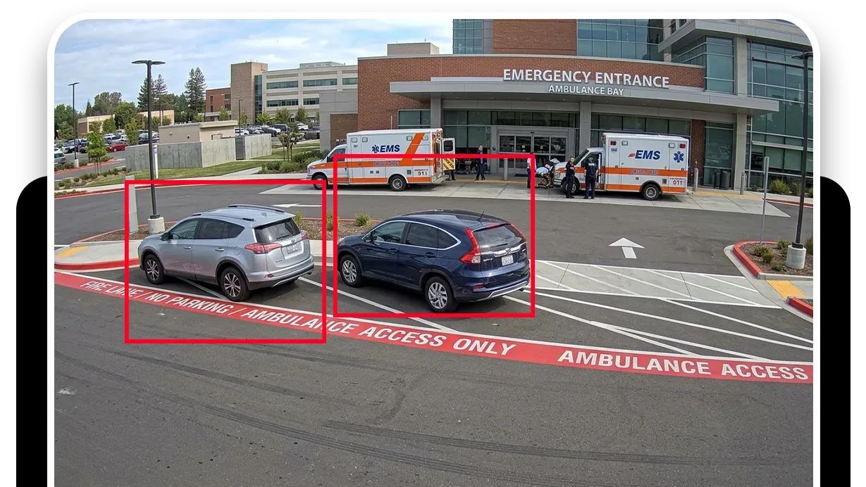 A console view of a storefront fire lane with a blue car parked across the yellow hatching, outlined in red and labeled Illegal Parking Detected